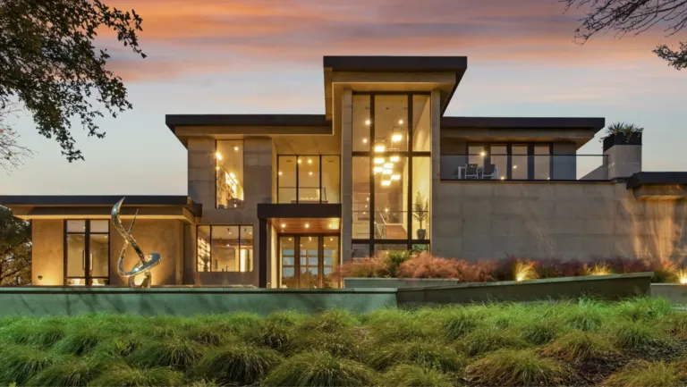Modern luxury residence with large windows lit at dusk