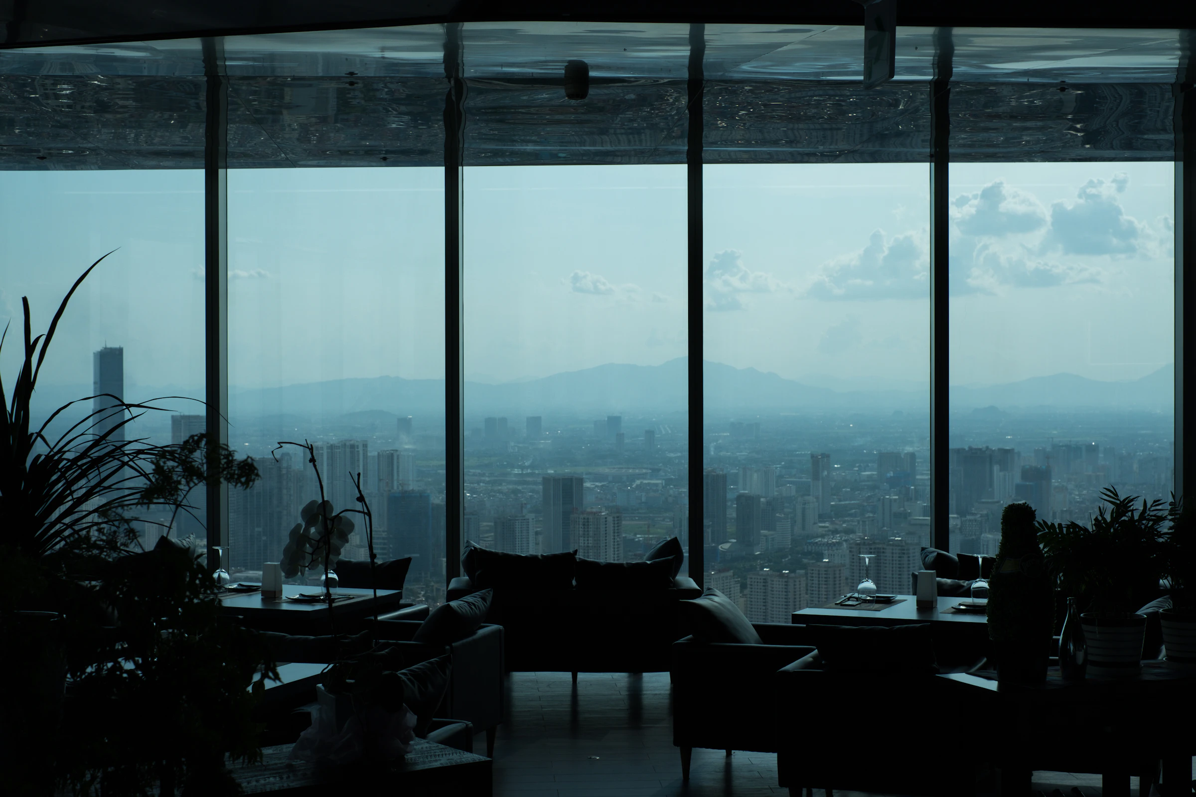 Penthouse living room with floor-to-ceiling windows overlooking the city at dusk
